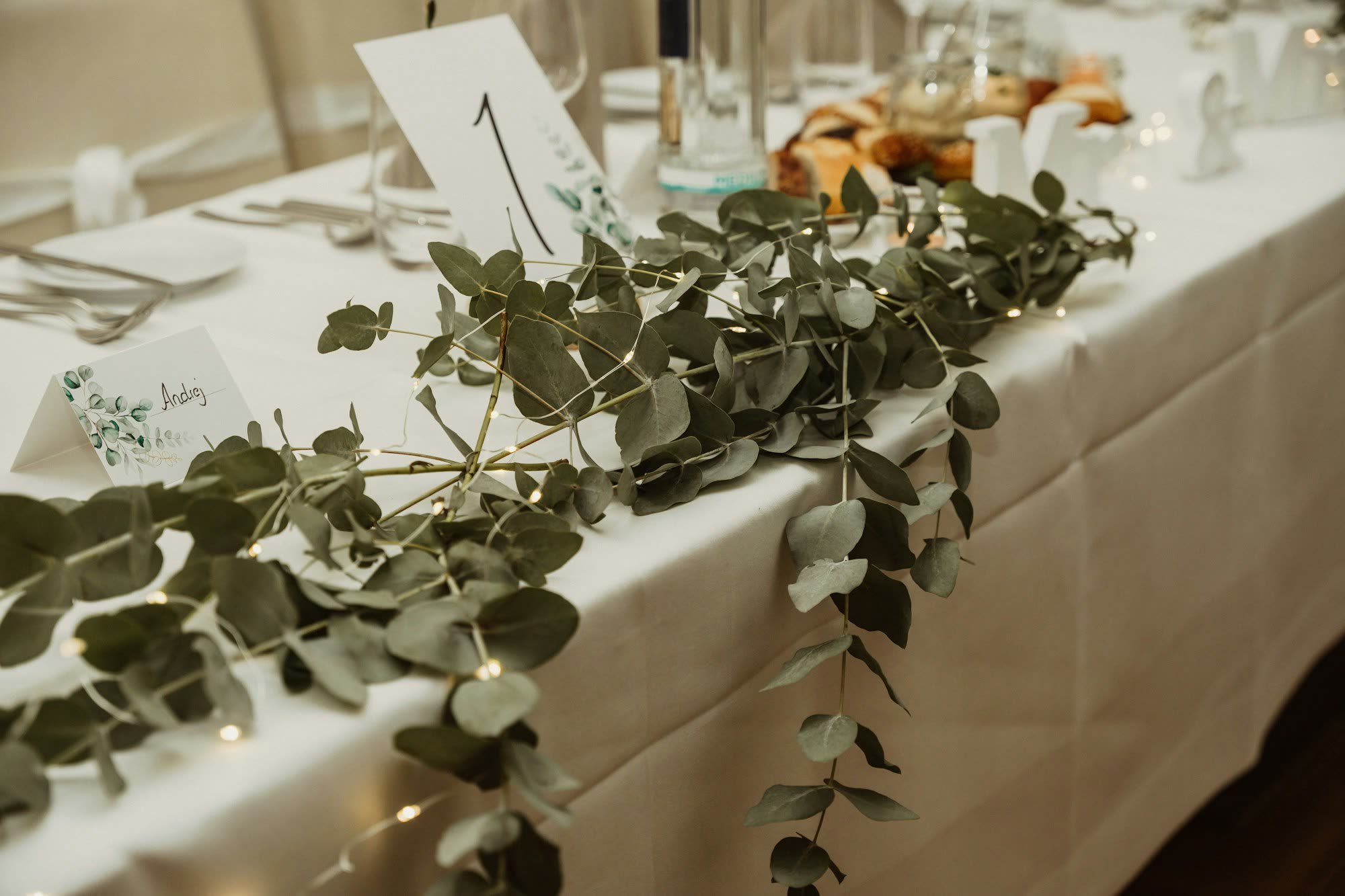 A eucalyptus garland and table-number card along a white-linen table, generic stock photo pending real venue photography.