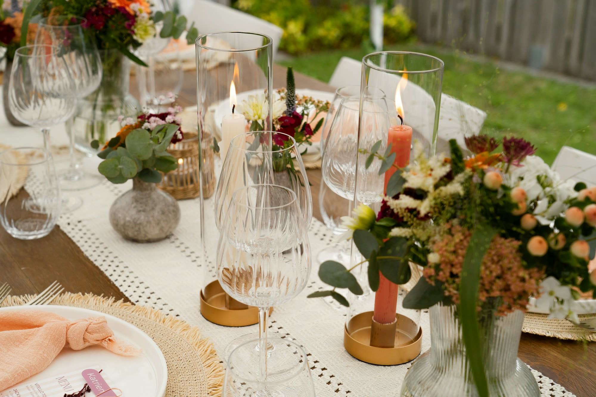 Candles and flower bouquets on a long table set up outdoors, generic stock photo pending real venue photography.