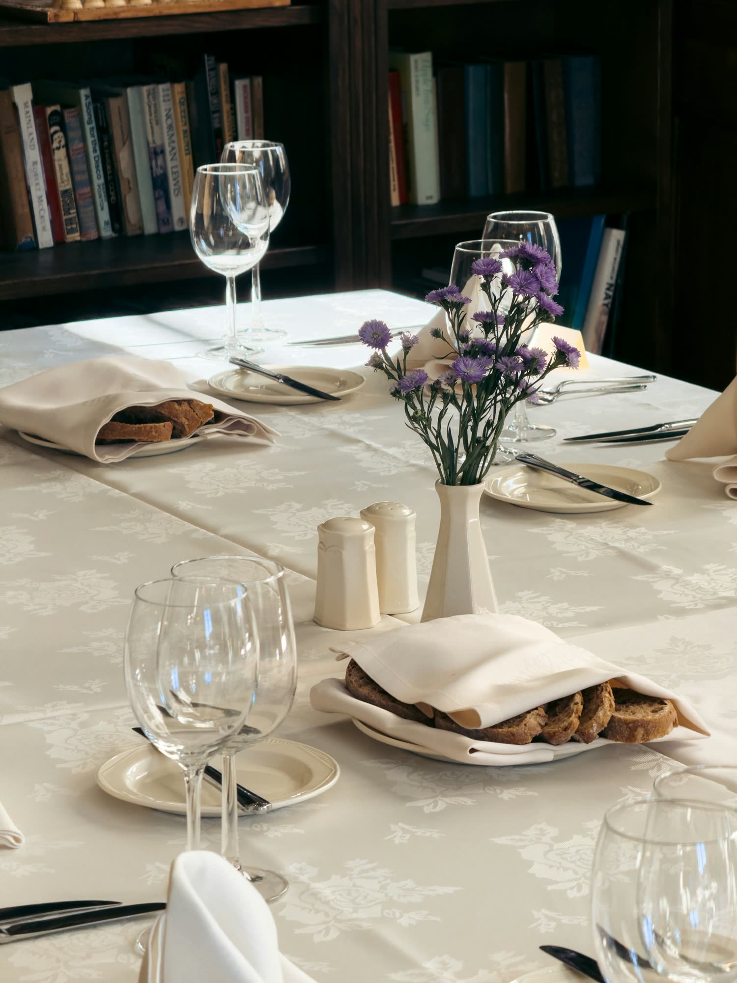 A white-linen table set with a small vase of flowers, bread and wine glasses, generic stock photo pending real venue photography.