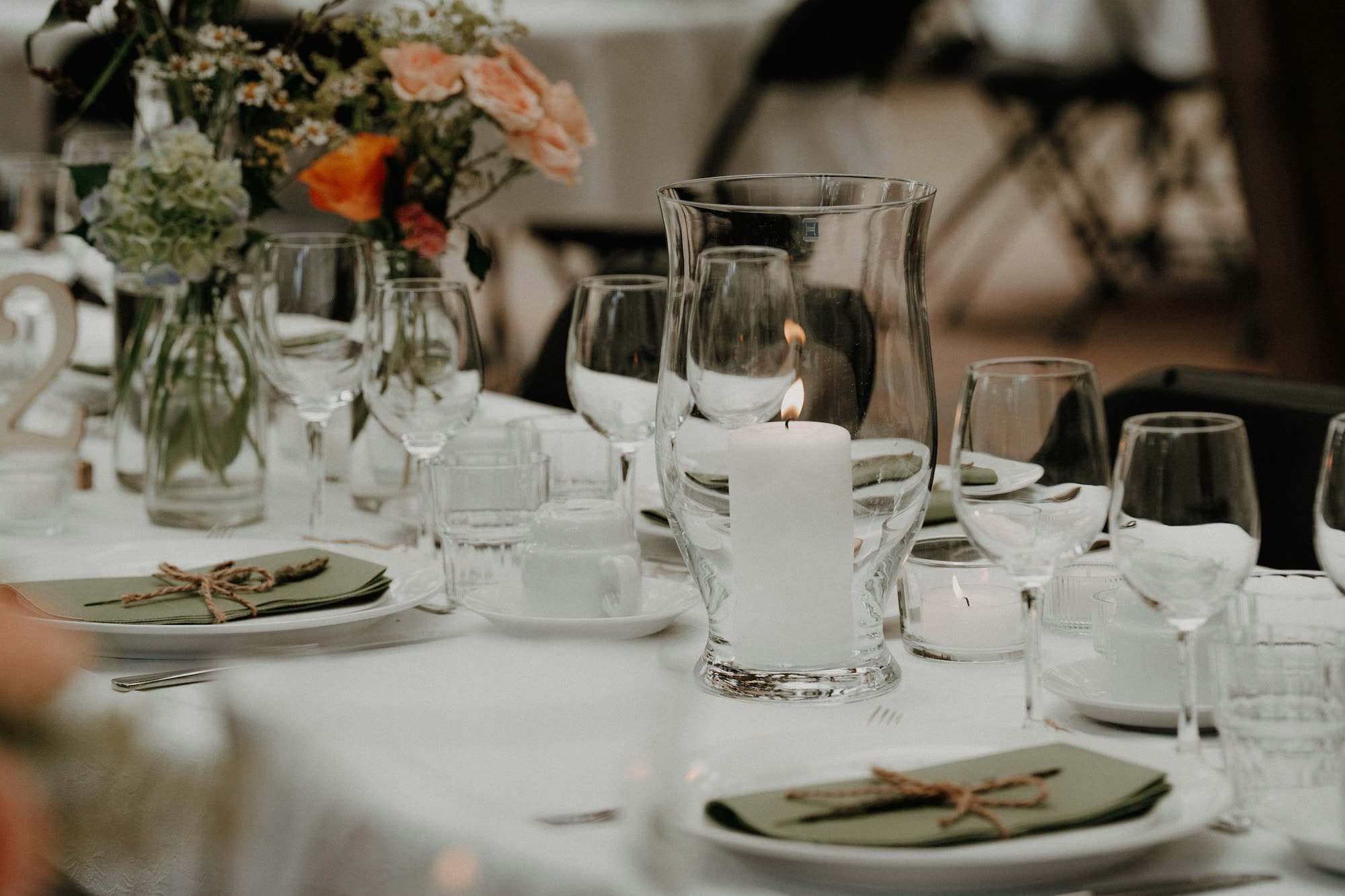 A table set with flowers, glasses and napkin-wrapped plates, generic stock photo pending real venue photography.