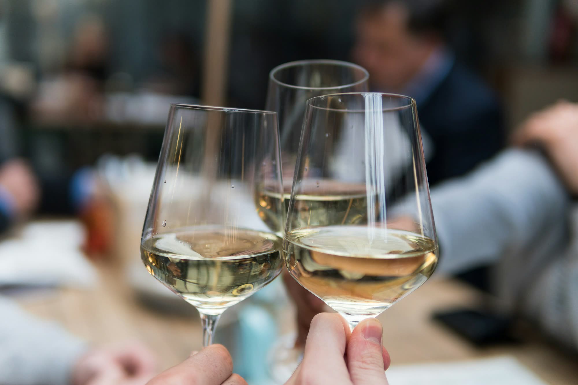 Two glasses of white wine clinking at a table, generic stock photo pending real venue photography.